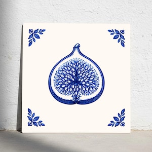Puede incluir: Azulejo cerámico cuadrado con una ilustración de higo azul. El higo está cortado por la mitad, mostrando el interior. Acentos florales azules en las esquinas sobre un fondo blanco. Apropiado para la decoración de cocina o baño, mide aprox. 20 cm x 20 cm.