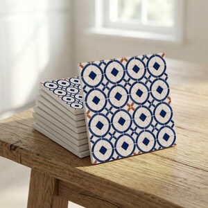 Coastal Mediterranean patterned ceramic tiles forming a clean repeating grid with minimal blue motifs.