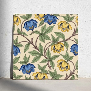 Könnte beinhalten: Eine quadratische Fliese mit einem sich wiederholenden botanischen Muster auf cremefarbenem Hintergrund. Das Design besteht aus blauen und gelben glockenförmigen Blüten mit dunklen Mitten, verbunden durch braune Stiele und grüne Blätter.