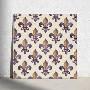 Puede incluir: Un azulejo cuadrado con un patrón repetitivo de símbolos de flor de lis dispuestos en cuadrícula. Cada flor de lis está dividida verticalmente, con una mitad de color morado intenso y la otra mitad de color amarillo dorado, sobre un fondo crema.