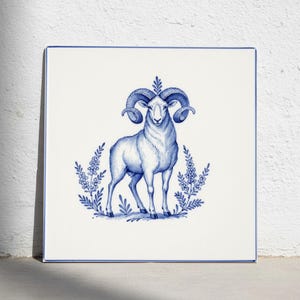 May include: A square white ceramic tile featuring a blue ink-style illustration of a ram with large curved horns. The ram is centered and flanked by two symmetrical floral sprigs. The tile has a thin blue border along all four edges.