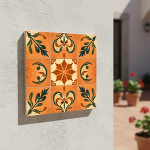 Op de afbeelding: Een vierkant wandkunstwerk bestaande uit negen decoratieve tegels. Elke tegel heeft een warme oranje achtergrond met verschillende ontwerpen in groen, crème en bruin. De ontwerpen omvatten bloemen- en geometrische patronen, waardoor een samenhangende en artistieke weergave ontstaat.