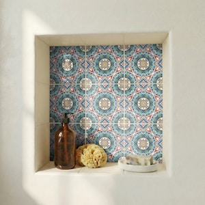 May include: A bathroom niche with patterned tiles in shades of blue, red, and cream. The niche contains a brown soap dispenser, a natural sponge, and a small white dish with soap.