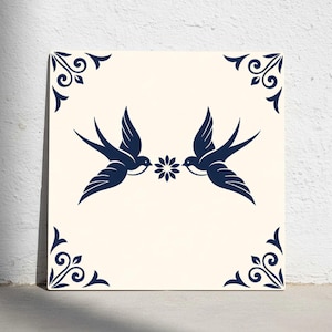 May include: Square ceramic tile with a cream background featuring two navy blue swallows facing each other, holding a flower. Navy blue decorative corner accents frame the image.