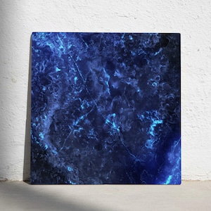 Könnte beinhalten: Quadratischer Leinwanddruck mit einem dunkelblauen Marmormuster, das durch hellere blaue Adern und Akzente hervorgehoben wird. Das abstrakte Design erinnert an eine himmlische oder ozeanische Szene mit strukturierter Oberfläche.