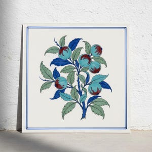 Könnte beinhalten: Eine quadratische Keramikfliese mit einer zentralen botanischen Illustration einer Pflanze mit hellblauen Beeren, dunkelroten Zentren sowie gezackten grünen und blauen Blättern. Das Motiv ist von einem dünnen blauen Rand auf weißem Grund umrahmt.