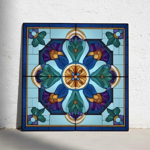 Puede incluir: Panel cuadrado de vidriera con un diseño floral simétrico. La obra presenta una flor central con pétalos azules, verdes y dorados, enmarcada por un borde azul y morado. El fondo es azul claro.
