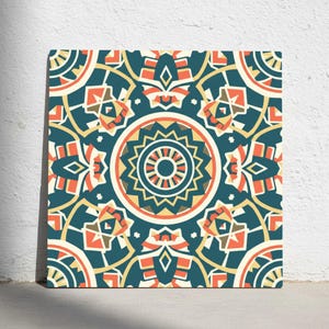 May include: Square canvas art featuring a symmetrical geometric pattern. The design incorporates teal, orange, yellow, and cream colors. The central focus is a circular motif with radiating lines, surrounded by repeating shapes.