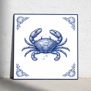 May include: Square ceramic tile featuring a detailed blue crab illustration on a white background. The crab is centered, with decorative seashell and scrollwork accents in each corner. The tile has a dark blue border.