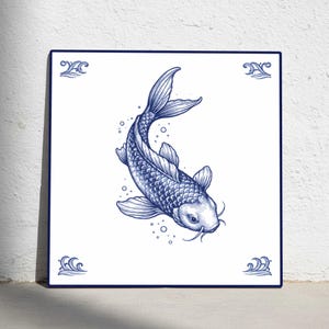 May include: Square ceramic tile with a blue and white koi carp illustration. The fish is depicted swimming diagonally, with bubbles around it. Decorative wave patterns are in each corner of the tile, which is a square.