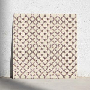 Puede incluir: Un azulejo cuadrado con un patrón geométrico repetitivo de círculos entrelazados en tono morado oscuro sobre un fondo de color crema sólido. El diseño consiste en anillos uniformes de líneas finas que se superponen en una cuadrícula.