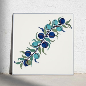 Puede incluir: Un azulejo de cerámica cuadrado con una ilustración botánica pintada a mano de una rama con frutos redondos azules y verde azulados y hojas verdes. El diseño está centrado sobre un fondo blanco con un borde fino de color azul.