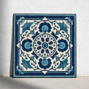 Può includere: Piastrella decorativa quadrata con un motivo floreale dettagliato nei toni del blu e del bianco. Il design presenta un motivo circolare centrale circondato da fiori e foglie stilizzate, incorniciato da un bordo blu scuro.