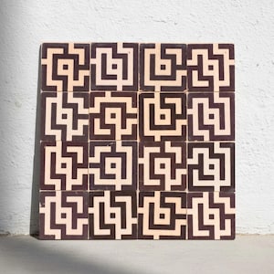 Peut inclure: Douze carreaux carrés disposés en grille. Chaque carreau présente un motif géométrique répétitif en marron foncé et crème. Le motif est une série de carrés et de lignes interconnectés, créant un effet de labyrinthe. Les carreaux sont probablement pour le revêtement de sol ou la décoration murale.