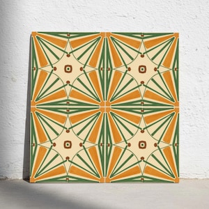 Op de afbeelding: Een vierkante decoratieve tegel met een herhalend geometrisch patroon in crème, donkergroen en gebrand oranje. Het ontwerp bestaat uit kruisende lijnen die stervormen vormen met stralende segmenten en kleine bruine vierkantjes in het midden.