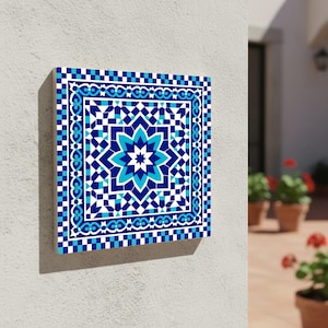 May include: Square wall art with a geometric mosaic design in blue and white. The central motif is a stylized eight-pointed star, surrounded by intricate patterns and a checkered border. The artwork is mounted on a white wall.