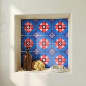 May include: A bathroom alcove featuring blue patterned tiles, a brown soap dispenser, a natural sponge, and a white soap dish with soap. The tiles display a geometric design in red, pink, and white.