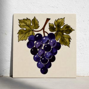 Może przedstawiać: Kwadratowa płytka ceramiczna z ręcznie malowaną ilustracją kiści fioletowych winogron, zielonych liści i brązowej łodygi. Winogrona są cieniowane, aby uzyskać efekt trójwymiarowy, na kremowym tle.