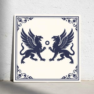 Könnte beinhalten: Quadratische Fliese mit cremefarbenem Hintergrund und marineblauem Rand. Das Design zeigt zwei marineblaue Greife mit Flügeln, die sich gegenüberstehen, mit einem kleinen Kreis dazwischen. Dekorative Elemente zieren die Ecken.