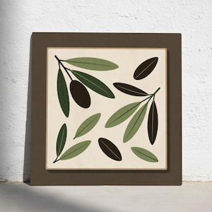 May include: A framed art print featuring a botanical illustration of olive branches and olives. The artwork showcases green and dark olive-colored leaves and olives against a cream background, framed in a brown border. The print is square and suitable for home decor.