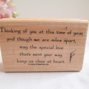 Pode incluir: Um carimbo de borracha retangular de madeira com o texto impresso em preto: Thinking of you at this time of year, and though we are miles apart, may the special love that's sent your way keep us close at heart. © 2002 STAMPIN' UP!