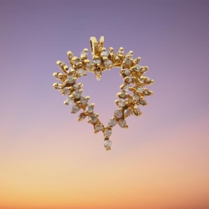 May include: A gold heart-shaped pendant with a diamond-like design. The pendant is set against a purple and orange gradient background.