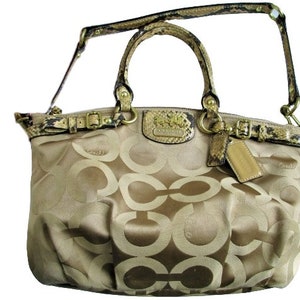 May include: A beige Coach handbag with a snakeskin strap and gold hardware. The bag features a large 'C' pattern on the front.
