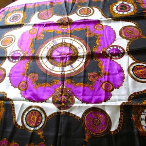 May include: A square silk scarf with a repeating pattern of clocks and ornate gold detailing. The scarf features a color palette of black, white, purple, and gold. The clocks have Roman numerals and are surrounded by decorative elements.
