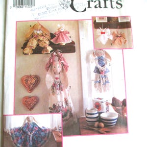 Puede incluir: Patrón de Simplicity Crafts con varias manualidades de conejos hechas a mano. La imagen muestra varias muñecas de conejos en diferentes estilos, incluyendo tela y elementos decorativos. El número de patrón es 7253.