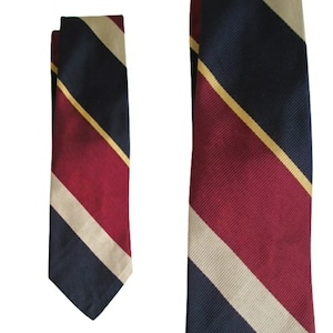 Puede incluir: Una corbata a rayas con rayas azul marino, burdeos y crema. La corbata tiene un patrón de rayas diagonales.