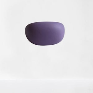 May include: A solid, oval-shaped object in a deep purple hue. The smooth, rounded form is set against a plain white background, creating a minimalist aesthetic. The object appears to be floating.