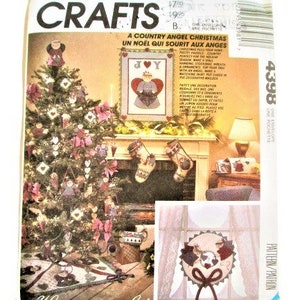 Puede incluir: Un patrón vintage de McCall's Crafts para una Navidad de ángel campestre. El patrón incluye instrucciones para hacer un árbol de Navidad, calcetines, una corona y una decoración de pared. El patrón se titula "A Country Angel Christmas" y "Un Noel Qui Sourit Aux Anges".