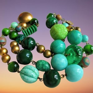 May include: A vintage beaded bracelet with a mix of gold, green, and turquoise beads. The bracelet features various bead shapes and sizes, including round, ribbed, and textured beads. The beads are strung together with gold-tone metal links.