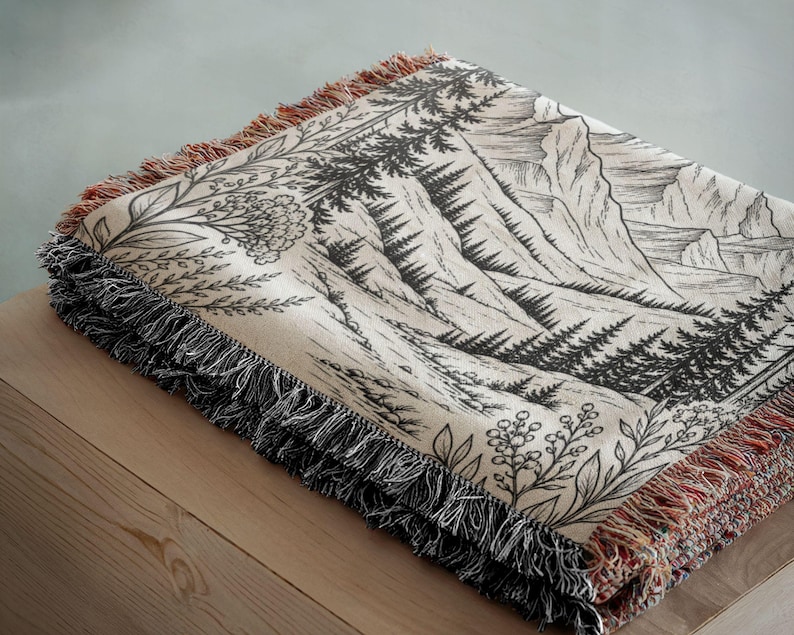 Personalized mountain woven blanket with custom couple names and date, featuring forest trees and rustic mountain landscape art, styled as cozy cabin wall decor for wedding, engagement, or anniversary gift.