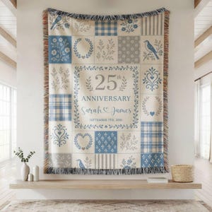 May include: A woven throw blanket featuring a blue and cream patchwork design with floral, bird, heart, and plaid patterns. The center displays the text 25th ANNIVERSARY, Sarah & James, and SEPTEMBER 7TH, 2001, framed by a decorative vine border.