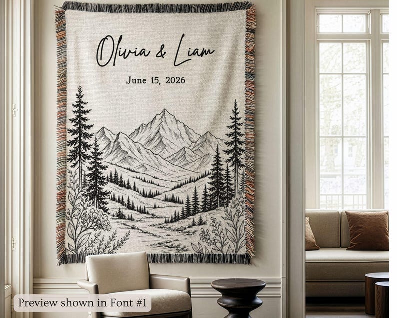 Personalized mountain woven blanket with custom couple names and date, featuring forest trees and rustic mountain landscape art, styled as cozy cabin wall decor for wedding, engagement, or anniversary gift.