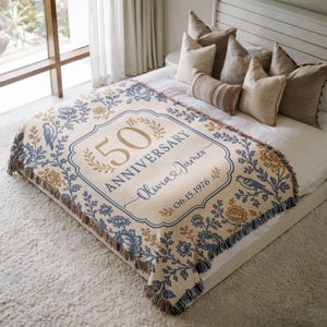 May include: Cream-colored woven throw blanket with a blue floral and bird design. The blanket features the text "50th Anniversary" with a personalized name and date. The blanket is fringed on the edges.