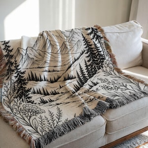Personalized mountain woven blanket with custom couple names and date, featuring forest trees and rustic mountain landscape art, styled as cozy cabin wall decor for wedding, engagement, or anniversary gift.