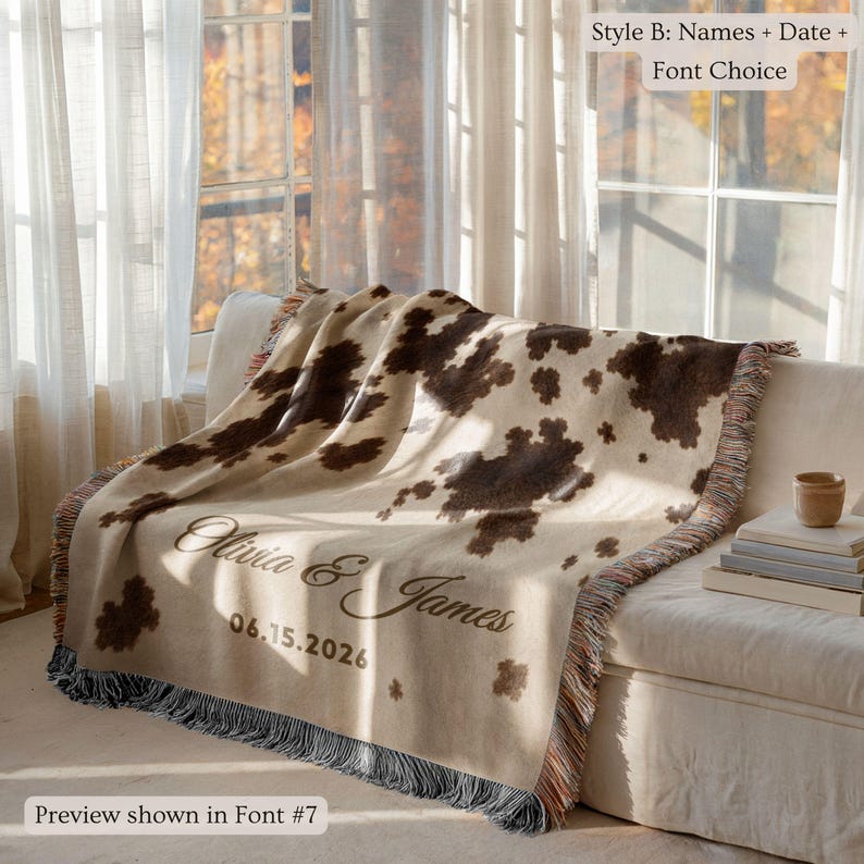 Personalized cow print woven blanket with custom couple names and wedding date, brown and cream western pattern, rustic farmhouse wall decor, fringe edges, and cozy country wedding keepsake style.