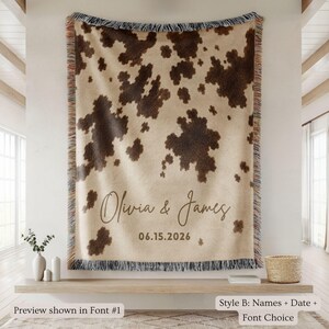 Personalized cow print woven blanket with custom couple names and wedding date, brown and cream western pattern, rustic farmhouse wall decor, fringe edges, and cozy country wedding keepsake style.