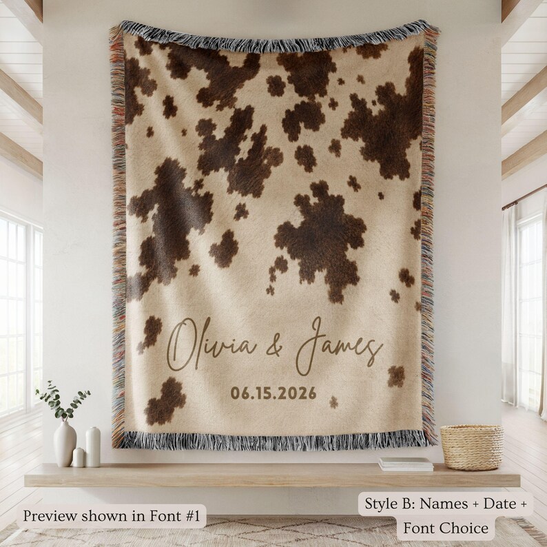 Personalized cow print woven blanket with custom couple names and wedding date, brown and cream western pattern, rustic farmhouse wall decor, fringe edges, and cozy country wedding keepsake style.