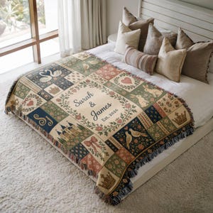 May include: A woven throw blanket featuring a patchwork design with illustrations of swans, rabbits, birds, crowns, castles, and hearts. The center displays a floral wreath surrounding the text Sarah & James Est. 2026. The blanket has fringed edges.