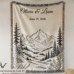 Personalized mountain woven blanket with custom couple names and date, featuring forest trees and rustic mountain landscape art, styled as cozy cabin wall decor for wedding, engagement, or anniversary gift.