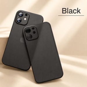 May include: Two matte black smartphone cases with a smooth finish. One case features a square camera cutout with two visible lenses and a flash, while the other case has a solid back. The text Black is printed in the upper right corner.