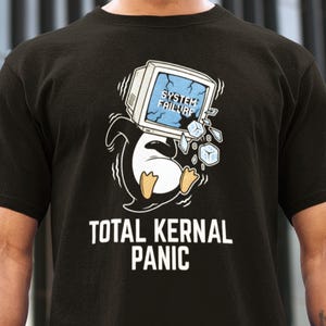 May include: Black t-shirt featuring a cartoon penguin with a computer monitor on its head, with the words "SYSTEM FAILURE" and "TOTAL KERNAL PANIC". The penguin is white, black, and yellow.