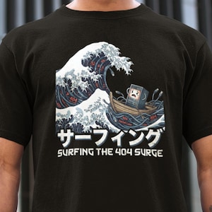 Może przedstawiać: Czarna koszulka z grafiką komputera w łodzi, surfującego na fali z komunikatami o błędach "404". Fale są w stylu "Wielkiej Fali w Kanagawie". Tekst brzmi "Surfing the 404 Surge" w języku angielskim i japońskim.