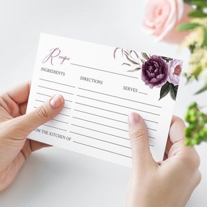 Può includere: Carta di ricetta stampabile con un design floreale con fiori viola e rosa. La carta ha sezioni per ingredienti, istruzioni e porzioni. Include anche il testo "Ricetta" e "Dalla cucina di".