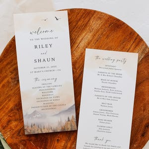 May include: Wedding stationery set featuring a welcome card and a wedding party program. The welcome card has a watercolor mountain scene and the names "Riley and Shaun." The program lists the ceremony details and wedding party.