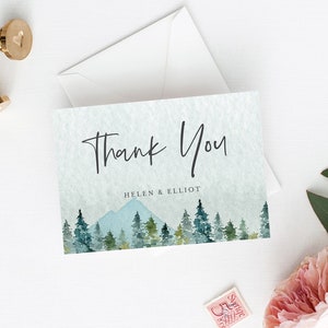 Puede incluir: Una tarjeta de agradecimiento con una ilustraci&oacute;n de acuarela de una cordillera y pinos. El texto "Thank You" est&aacute; escrito en letra cursiva negra. Debajo de la ilustraci&oacute;n, el texto "Helen & Elliot" est&aacute; escrito en negro.