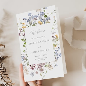 Może przedstawiać: Białe zaproszenie ślubne z kwiatową obwódką. Zaproszenie zawiera napis "Witamy" i zawiera nazwiska Elodie Granger i Ethan Miller, datę 25 sierpnia 20XX oraz lokalizację St. Mary's Church, Minnesota.